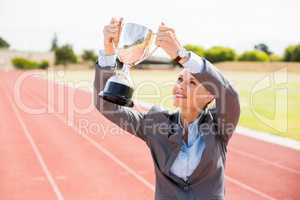 Happy businesswoman holding up a trophy