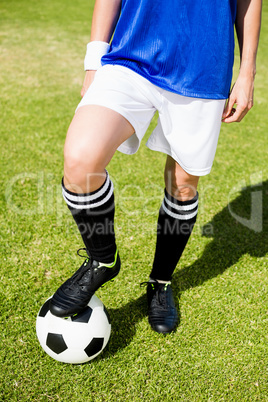 Female football player standing with her feet on ball