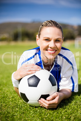 Portrait of female football player lying on football field with