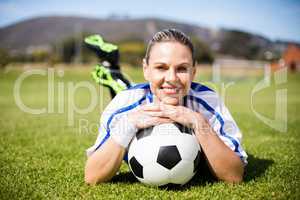 Portrait of female football player lying on football field with