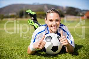 Portrait of female football player lying on football field and s