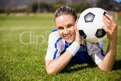 Portrait of female football player lying on football field and h