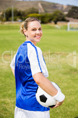 Portrait of happy female football player standing with a ball