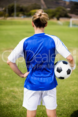 Rear view of female football player standing with a ball