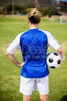 Rear view of female football player standing with a ball