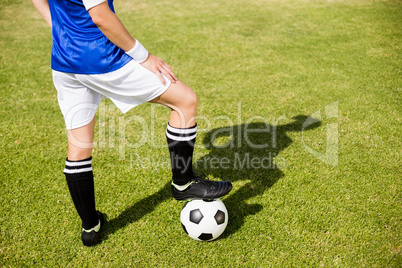 Female football player standing with her feet on ball