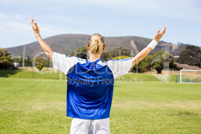 Rear view of female football player posing after a victory