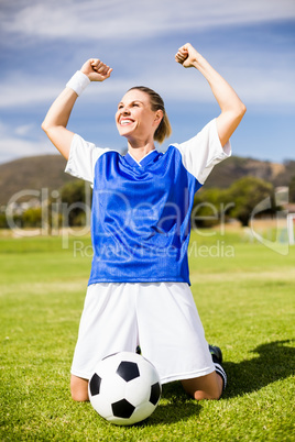 Excited football player kneeling in stadium