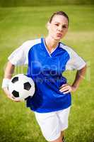 Female football player standing with a ball