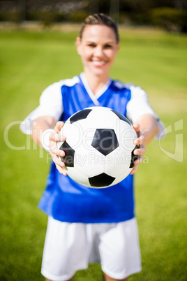 Female football player standing with ball