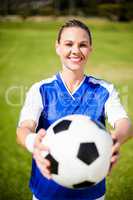 Female football player standing with ball