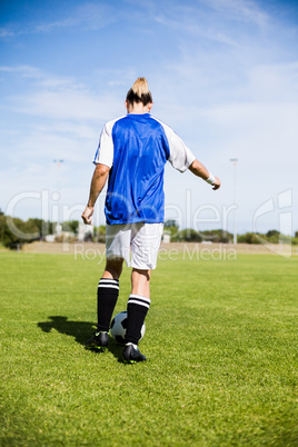 Rear view of female football player practicing soccer Rear view of female football player practicing soccer