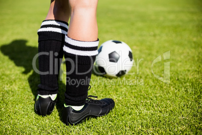 Feet of a female football player and a ball