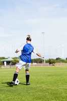 Rear view of female football player practicing soccer