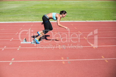 Female athlete running from starting blocks