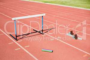 Hurdle, relay baton and a starting block kept on a running track
