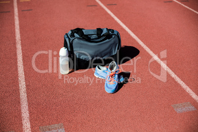 Sports bag, shoes and a water bottle kept on a running track