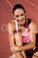 Portrait of female athlete sitting on running track