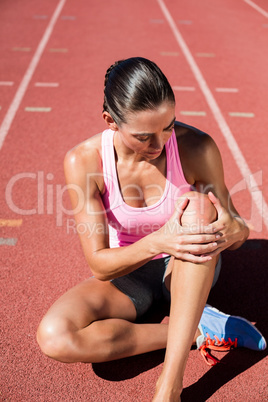 Female athlete with pain in knee joint on running track