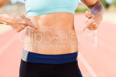 Mid section of female athlete pointing on her belly