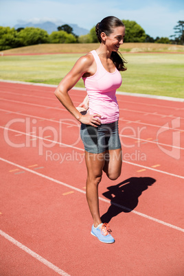 Happy female athlete warming up on the running track