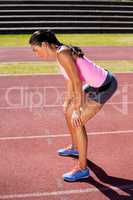 Tired female athlete standing on running track