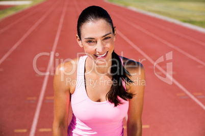 Portrait of happy female athlete standing on running track