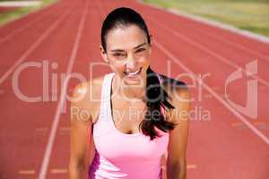 Portrait of happy female athlete standing on running track