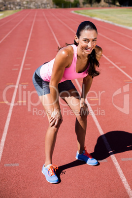 Portrait of tired female athlete standing on running track