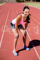 Portrait of tired female athlete standing on running track