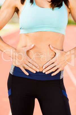 Mid section of female athlete touching her belly