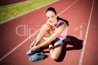 Portrait of happy female athlete tying her running shoes