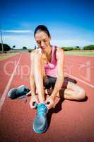 Happy female athlete tying her running shoes