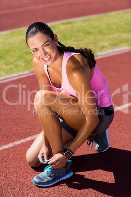 Portrait of happy female athlete tying her running shoes
