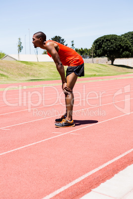 Tired athlete standing on running track