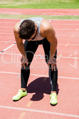 Tired athlete standing on running track