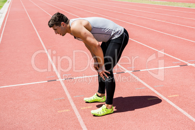 Tired athlete standing on running track