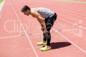 Tired athlete standing on running track