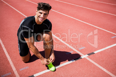 Portrait of male athlete tying her shoe laces on running track