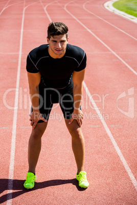 Tired athlete standing on running track