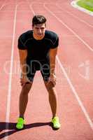 Tired athlete standing on running track