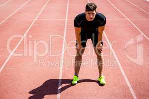 Tired athlete standing on running track