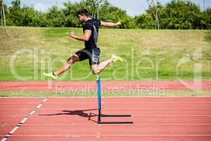 Athlete jumping above the hurdle