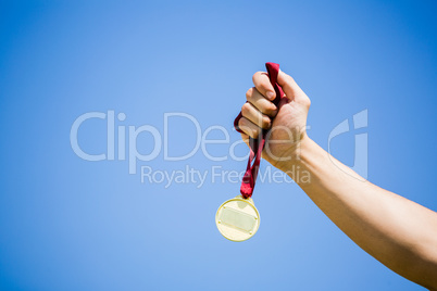 Athlete hand holding gold medal after victory