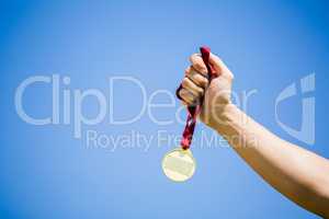 Athlete hand holding gold medal after victory