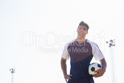 Happy football player standing with a ball