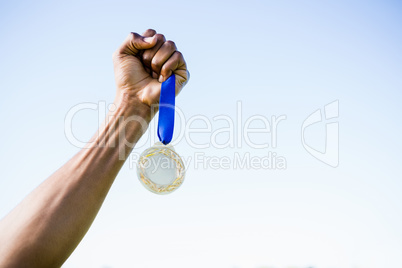 Athletes hand holding gold medal after victory