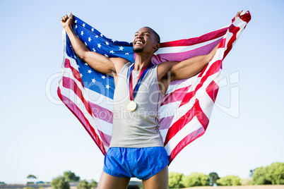 Athlete posing with american flag and gold medals around his nec