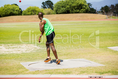 Male athlete throwing shot put ball