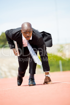 Businessman with laptop ready to run